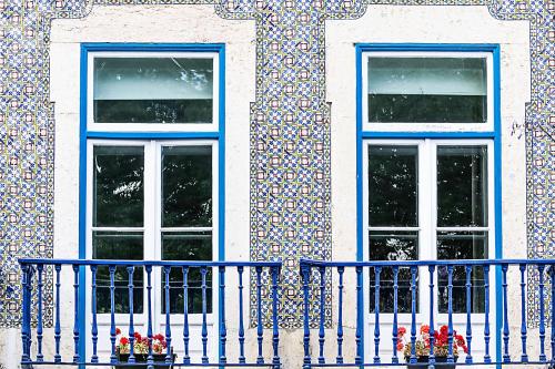 a building with two windows and a blue fence at Emporium Lisbon Suites in Lisbon
