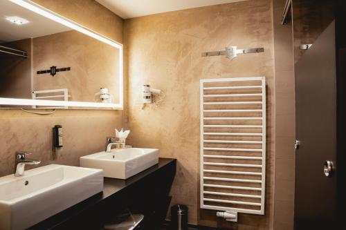 a bathroom with two sinks and a mirror at HELD - Hotel & Spa , 4 Sterne Superior, Zillertal in Fügen