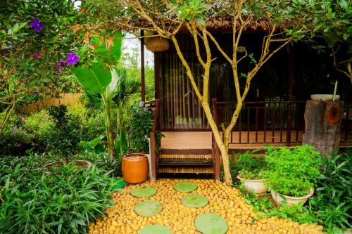 a garden with a bird house and a tree at Tĩnh Lạc Viên Homestay Bảo lộc in Bao Loc