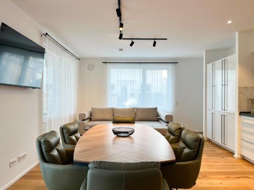 a dining room with a wooden table and leather chairs at YUVA HOMES Germering - 100m2 - nahe München - 2 Bäder - Garten&Terrasse - S-Bahn in Germering
