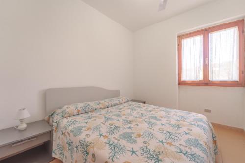 a white bedroom with a bed and a window at Appartamenti Gli Orizzonti - Goelba in Marina di Campo