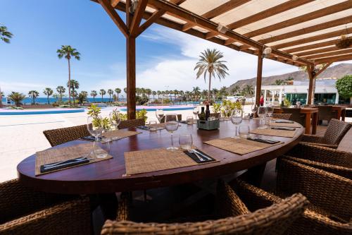a wooden table with wine glasses on a patio at Playitas Hotel - Sports Resort in Las Playas