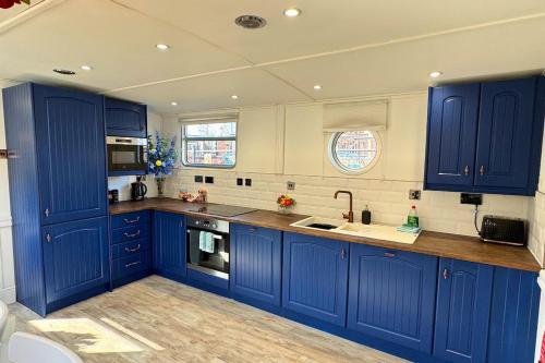 a kitchen with blue cabinets and a sink at The Swan Flotel - Barton Marina in Burton upon Trent