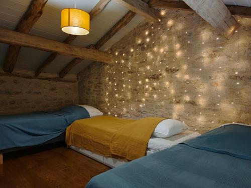 deux lits dans une chambre avec des lumières sur le mur dans l'établissement Gite Valades - avec piscine et vue, à Saint-Antonin