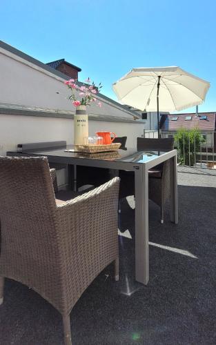a table with two chairs and an umbrella at Warnemünde Strandnest 24350 in Warnemünde
