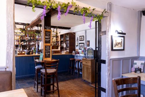 a bar with wooden stools and purple flowers at Cromwell Lodge Hotel by Greene King Inns in Banbury