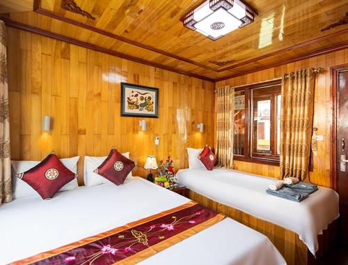 two beds in a room with wooden walls at Halong Ocean Cruise 6 in Ðảo Cát Bà