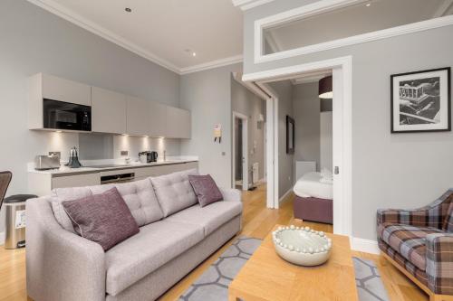 a living room with a couch and a kitchen at Destiny Scotland - Princes Street Residence in Edinburgh