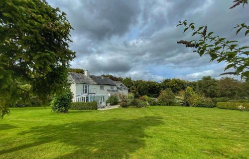 a white house with a large green yard at Cherryford House in Gidleigh