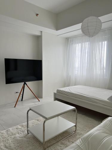 a white room with a bed and a table at Cloud Space Studio near Eastwood in Manila