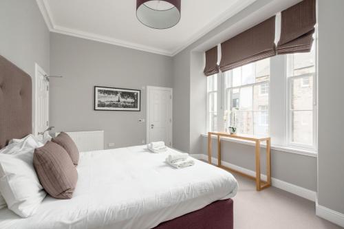 a white bedroom with a bed and a window at Destiny Scotland - Princes Street Residence in Edinburgh