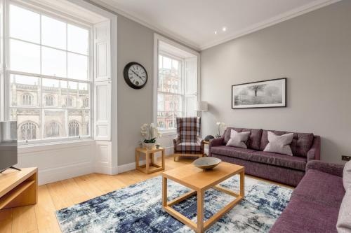 a living room with a couch and a clock on the wall at Destiny Scotland - Princes Street Residence in Edinburgh