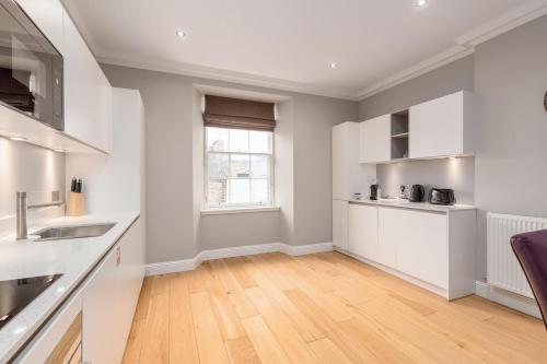 a kitchen with white cabinets and a wooden floor at Destiny Scotland - Princes Street Residence in Edinburgh