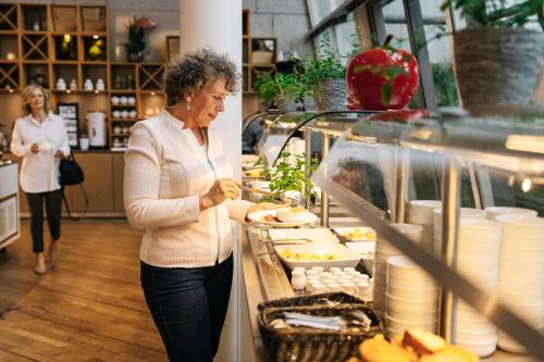 a woman standing in a store preparing food at Kongresshotel Potsdam am Templiner See in Potsdam