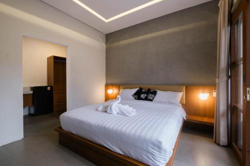 a bedroom with a white bed with a swan on it at Kemuning Living Sanur in Sanur