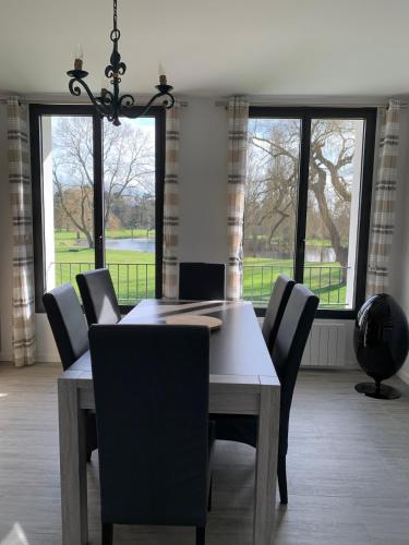 une salle à manger avec une table, des chaises et des fenêtres dans l'établissement Appartement Le Domaine De Louis, à Croisy-sur-Eure