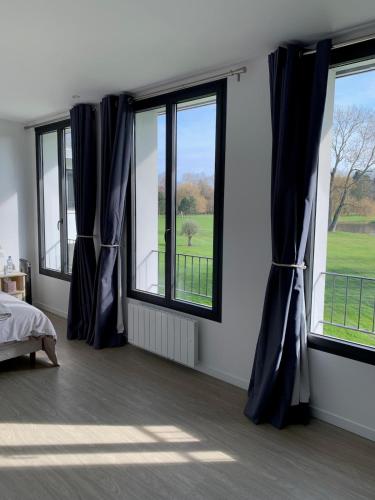 - une chambre avec trois fenêtres dotées de rideaux bleus dans l'établissement Appartement Le Domaine De Louis, à Croisy-sur-Eure