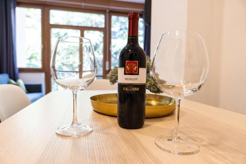 a bottle of wine and two wine glasses on a table at Flow Apartments WINKEL STUDIO in Merano