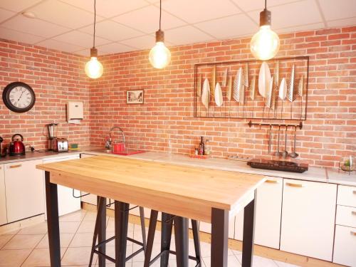 une cuisine avec une table en bois et un mur en briques dans l'établissement HOTEL DU BERRY - Loveroom avec Sauna, Hammam, Jacuzzi privatifs, à Reuilly