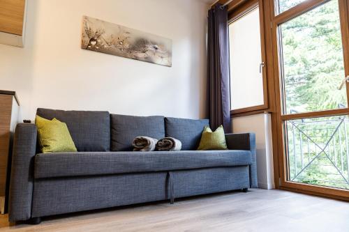 a blue couch in a living room with a window at Flow Apartments WINKEL STUDIO in Merano