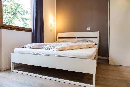 a white bed in a room with a window at Flow Apartments WINKEL STUDIO in Merano