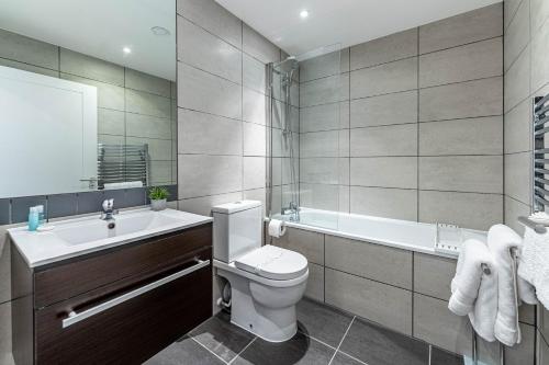 a bathroom with a toilet and a tub and a sink at Sussex House in Reading