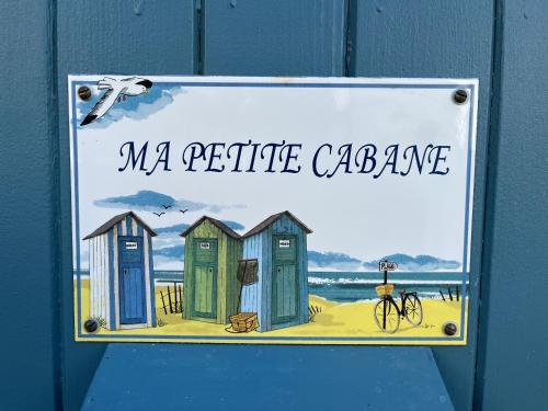 un panneau sur une porte bleue avec une photo de cabanes de plage dans l'établissement Ma Petite Cabane, à Saint-Martin-de-Ré