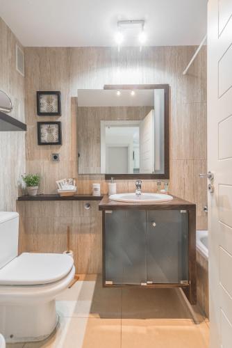 a bathroom with a toilet and a sink and a mirror at Home2Book Urban Retreat & Shared Pool Las Palmas in Las Palmas de Gran Canaria