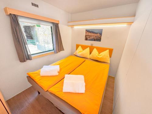 a yellow bed in a small room with a window at Lakeview Cannobio Camping & Resort in Cannobio