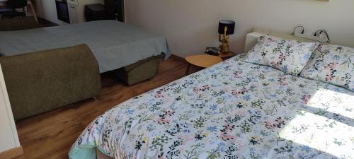 une chambre avec un lit avec une couette fleurie dans l'établissement Au JJR, à Châlons-en-Champagne