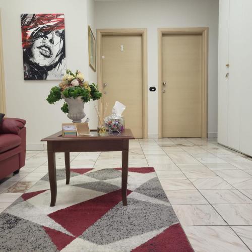 a living room with a table and a vase of flowers at Rainbow Sweet Rooms in Valmontone