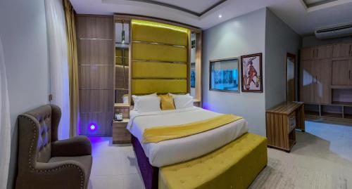 a bedroom with a large bed with a yellow headboard at Ceedapeg Hotels in Uyo