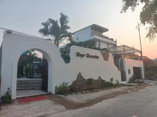 a white building with an arch in front of a building at Hugo Homestay in Phong Nha