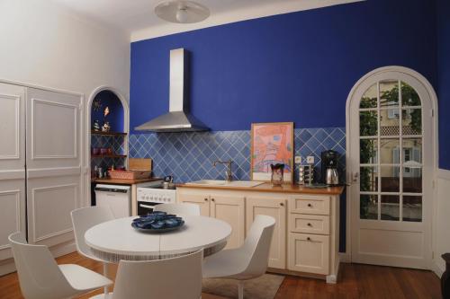 a kitchen with blue walls and a white table and chairs at Maison de Fogasses in Avignon