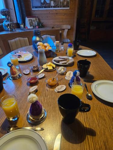 a wooden table with plates and glasses of orange juice at Espi-Stables Ferienhof Esterhammer in Liebenau