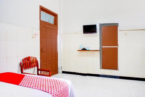 a room with a bed and a chair and a door at Collection O Darussalam Near Universitas Syiah Kuala Formerly Meurah Mulia in Banda Aceh