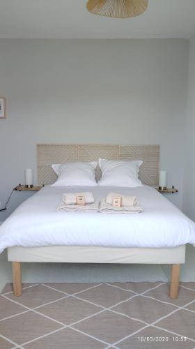 un lit blanc avec deux serviettes dessus dans l'établissement Studios ou Chambre SDB avec extérieur centre-ville Ribérac, à Ribérac