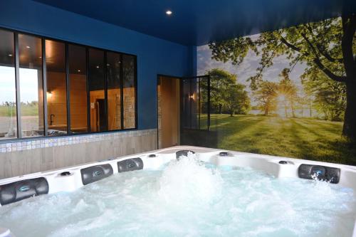 une baignoire jacuzzi dans une maison avec fenêtre dans l'établissement Domaine des Agapanthes Chambres d'hôtes et Spa, à Épreville