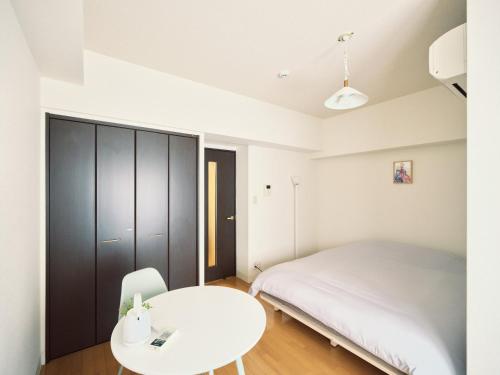 a bedroom with a white bed and a white table at vetta kumamoto sakuramachi 603 in Kumamoto