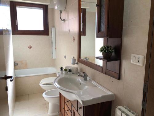 Un baño con lavabo, inodoro y espejo. en Casa Vinny, en La Maddalena