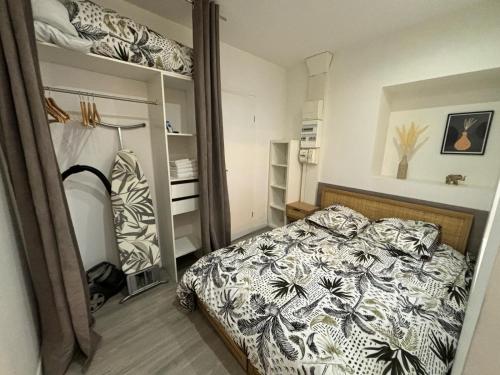 ein Schlafzimmer mit einem Bett mit einer schwarz-weißen Bettdecke in der Unterkunft Le Nid en Rotin Apartment in Montbéliard