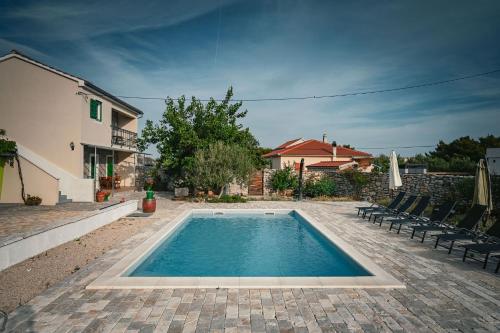 a swimming pool in a yard with chairs and a house at Marcelovi dvori in Pirovac