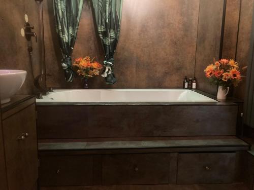 ein Badezimmer mit einer Badewanne mit zwei Blumen in der Unterkunft Gavin's Sea Pad in St. Leonards