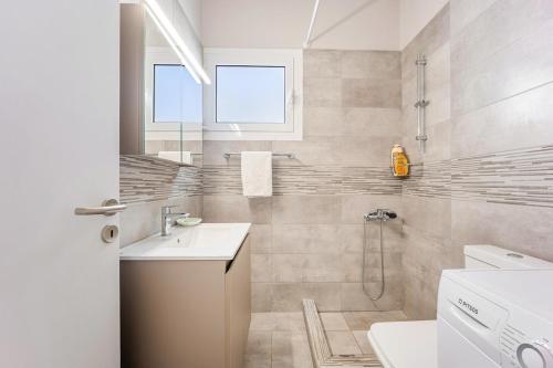a white bathroom with a sink and a shower at Villa Limanaki Lavrion Port in Kalopigado