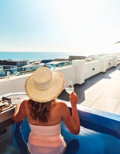 a woman sitting in a swimming pool with a glass of wine at Yzerfontein Villa Fantastica - No Loadshedding in Yzerfontein