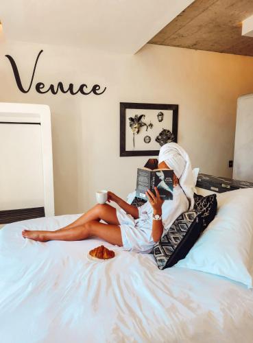 a woman laying on a bed reading a book at Yzerfontein Villa Fantastica - No Loadshedding in Yzerfontein