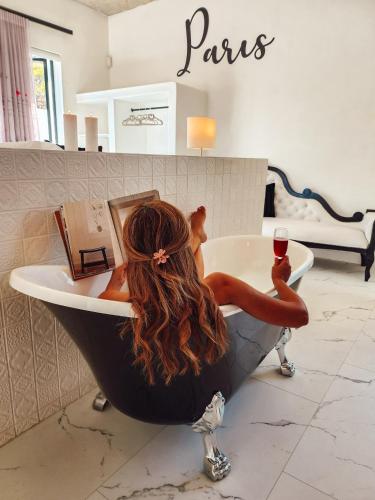 a woman sitting in a bath tub with a glass of wine at Yzerfontein Villa Fantastica - No Loadshedding in Yzerfontein
