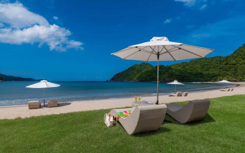a group of chairs and an umbrella on a beach at Miranda A 616 - Cozy Retreat at Pico De Loro Beach, Nasugbu Batangas in Nasugbu