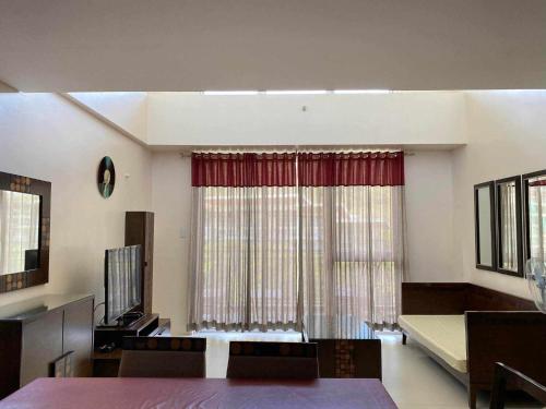 a living room with a large window with red curtains at Miranda A 616 - Cozy Retreat at Pico De Loro Beach, Nasugbu Batangas in Nasugbu