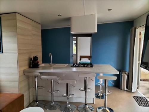 une cuisine avec des murs bleus et un comptoir avec des tabourets dans l'établissement Camping, au Muy